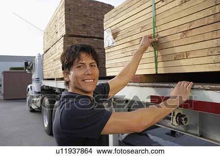 Young Man checking truck loaded with wood View Large Photo Image Picture - Young Man checking truck loaded with wood. Fotosearch