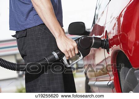 Young man filling car with gas at gas station, mid section View Large Photo Image Stock Image - Young man filling car with gas at gas station, mid section. Fotosearch