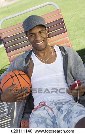 Stock Image - Young Man Holding Basketball, Portrait. Fotosearch