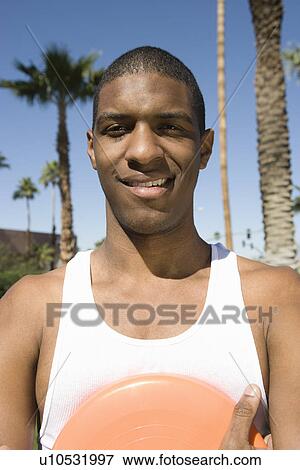 Young man holding frisbee, outdoors, portrait View Large Photo Image Stock Photo - Young man holding frisbee, outdoors, portrait. Fotosearch