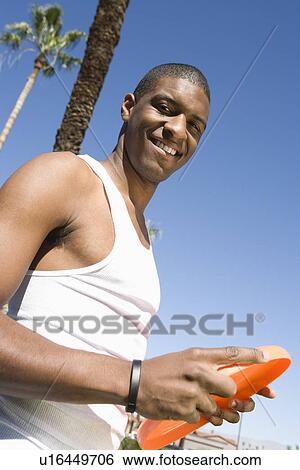 Stock Photograph - Young man holding frisbee, outdoors, portrait. Fotosearch