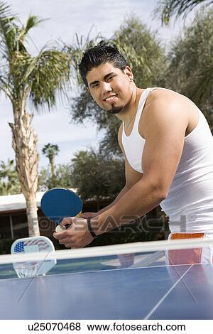 Stock Photo - Young Man Playing Ping-Pong by Swimming Pool. Fotosearch