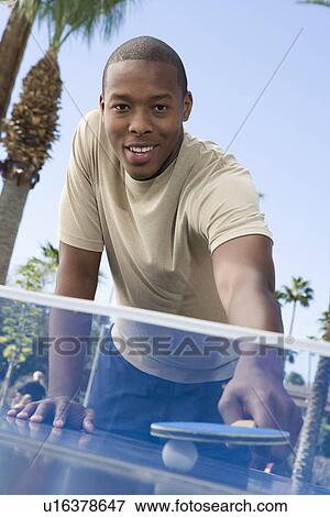 Stock Photo - Young man playing table tennis, portrait. Fotosearch