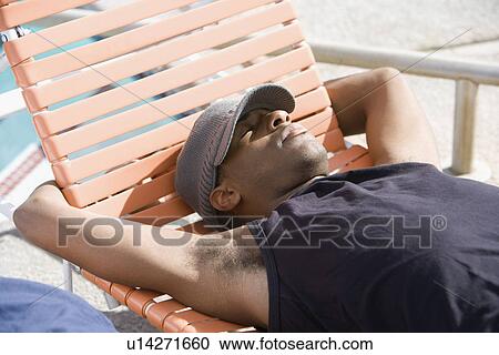 Stock Image - Young Man Relaxing by Swimming Pool. Fotosearch