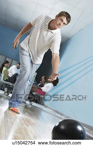 Picture - Young man releasing bowling ball, portrait. Fotosearch