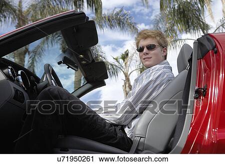 Young man sitting in convertible sports car, low angle view, side view View Large Photo Image Stock Image - Young man sitting in convertible sports car, low angle view, side view. Fotosearch