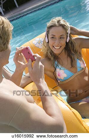 Stock Image - Young Man Taking Photograph on Woman in Inflatable Raft. Fotosearch