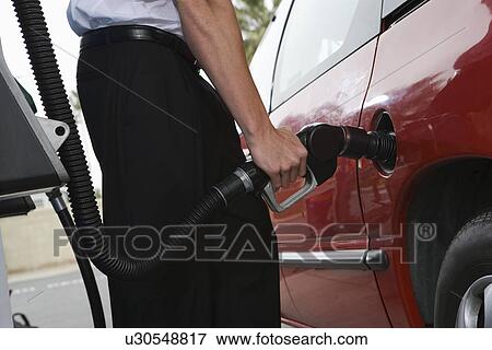 Stock Photo - Young man with fuel pump, mid section. Fotosearch
