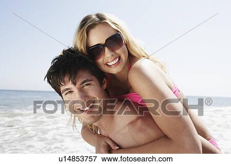 Young man with woman oh shoulders at beach, portrait View Large Photo Image Stock Photo - Young man with woman oh shoulders at beach, portrait. Fotosearch