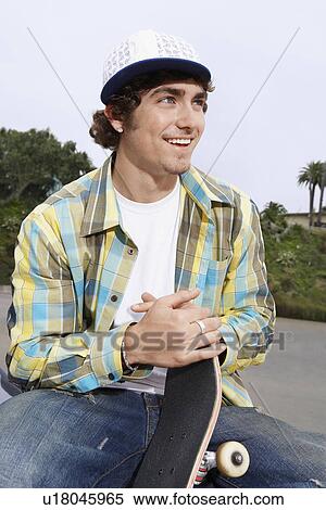 Stock Photography - Young skateboarder sitting outside. Fotosearch
