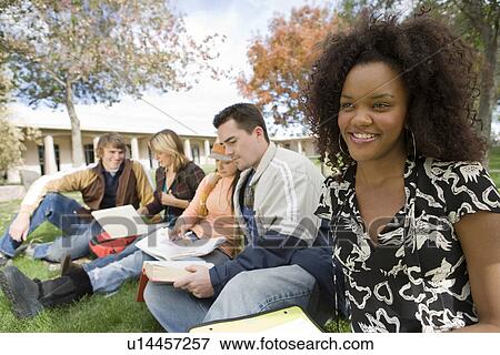 Stock Photo - Young students sitting on grass. Fotosearch