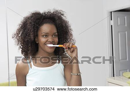 Young woman brushing teeth in bathroom View Large Photo Image Picture - Young woman brushing teeth in bathroom. Fotosearch