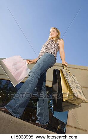 Young woman carrying shopping bags, outdoors View Large Photo Image Stock Photography - Young woman carrying shopping bags, outdoors. Fotosearch