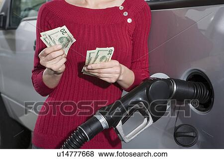 Stock Photo - Young woman counting money at service station. Fotosearch