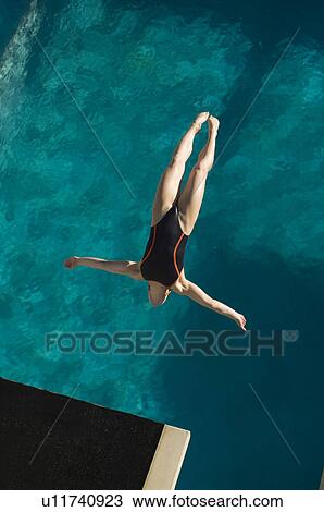 Stock Image - Young woman diving into swimming pool. Fotosearch
