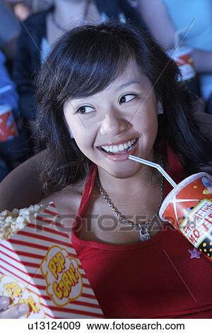Young Woman Drinking Soda, Watching Movie in movie theatre View Large Photo Image Stock Photo - Young Woman Drinking Soda, Watching Movie in movie theatre. Fotosearch