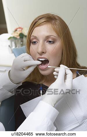 Stock Photography - Young woman having teeth examined at dentists. Fotosearch