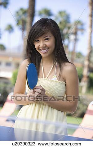 Stock Image - Young woman playing table tennis, portrait. Fotosearch
