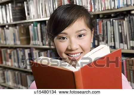 Picture - Young woman reading at library. Fotosearch