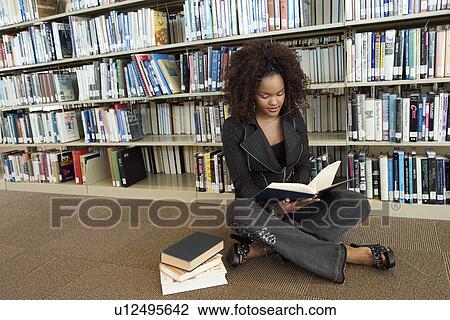Young woman sitting on library floor, reading View Large Photo Image Stock Image - Young woman sitting on library floor, reading. Fotosearch