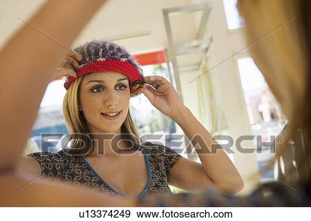 Young woman trying on hat in shop View Large Photo Image Stock Photo - Young woman trying on hat in shop. Fotosearch