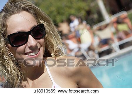 Young woman wearing sunglasses by pool, head and shoulders View Large Photo Image Stock Photo - Young woman wearing sunglasses by pool, head and shoulders. Fotosearch