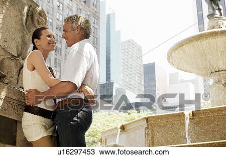 Stock Image - Affectionate couple embracing by fountain. Fotosearch