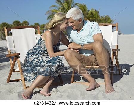 Affectionate senior couple on sunloungers on beach, holding hands View Large Photo Image Stock Photo - Affectionate senior couple on sunloungers on beach, holding hands. Fotosearch
