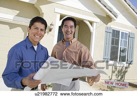 Stock Image - Architect showing house plans. Fotosearch