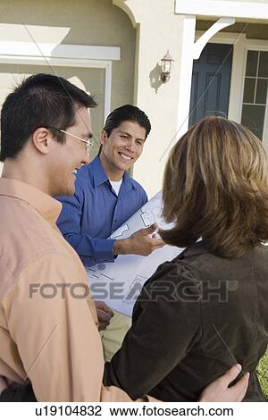 Stock Image - Architect showing plans to couple. Fotosearch