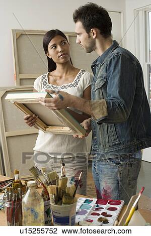 Stock Image - Artists Looking at Canvas in Studio. Fotosearch