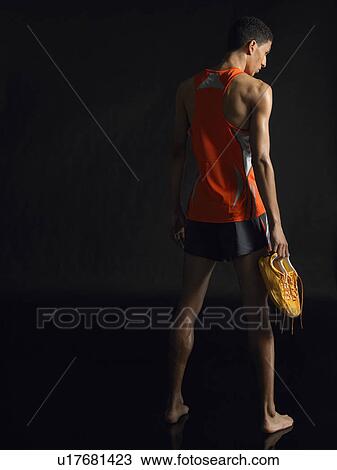 Athlete standing, holding shoes, back view View Large Photo Image Stock Image - Athlete standing, holding shoes, back view. Fotosearch