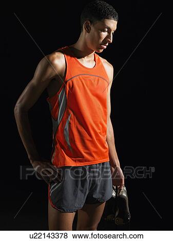 Athlete standing, holding shoes View Large Photo Image Stock Photo - Athlete standing, holding shoes. Fotosearch