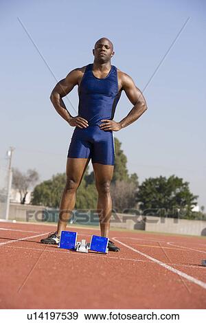 Athlete standing next to starting block, ready to run View Large Photo Image Stock Photo - Athlete standing next to starting block, ready to run. Fotosearch