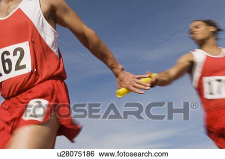 Stock Photograph - Athletes passing relay baton. Fotosearch