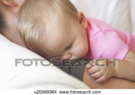 Baby sleeping on mother's shoulder, close up View Large Photo Image Picture - Baby sleeping on mother's shoulder, close up. Fotosearch