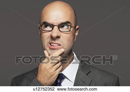 Bald businessman wearing glasses with hand on chin, making funny face View Large Photo Image Stock Image - Bald businessman wearing glasses with hand on chin, making funny face. Fotosearch