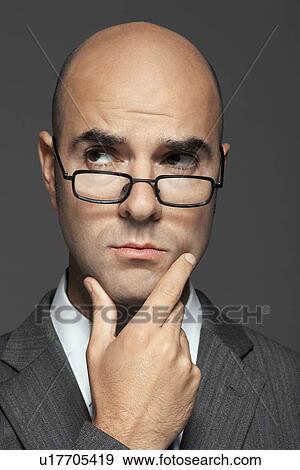 Bald man wearing glasses with hand on chin View Large Photo Image Stock Photo - Bald man wearing glasses with hand on chin. Fotosearch