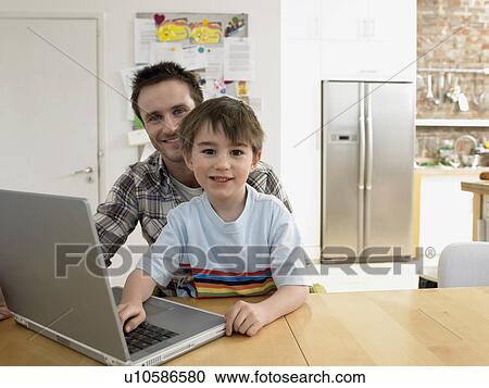 Boy (3-6) using laptop with father in kitchen, (portrait) View Large Photo Image Stock Image - Boy (3-6) using laptop with father in kitchen, (portrait). Fotosearch