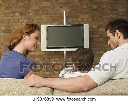 Boy (3-6) with parents on couch in living room View Large Photo Image Stock Photo - Boy (3-6) with parents on couch in living room. Fotosearch
