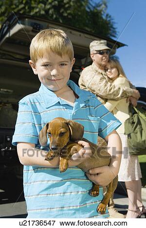 Stock Photo - Boy (5-6) holding dog, outdoors, (portrait). Fotosearch