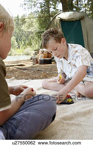 Boy (5-6) sitting at campsite, playing with toys with brother (7-9). View Large Photo Image Stock Image - Boy (5-6) sitting at campsite, playing with toys with brother (7-9).. Fotosearch