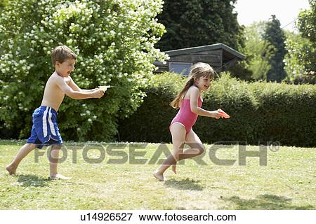 Boy shooting girl with water pistol in back yard View Large Photo Image Stock Photo - Boy shooting girl with water pistol in back yard. Fotosearch