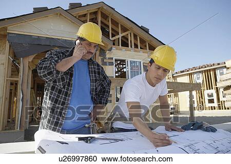 Stock Image - Builders building a house. Fotosearch