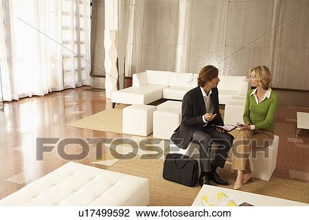Stock Image - Business couple talking in living room. Fotosearch