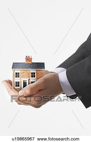 Stock Photo - Business man holding model house in cupped hands, view of hands. Fotosearch