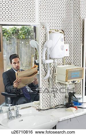 Stock Photograph - Business man reading newspaper in barber shop. Fotosearch