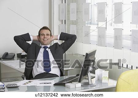 Business man relaxing at desk in office, smiling, portrait View Large Photo Image Stock Image - Business man relaxing at desk in office, smiling, portrait. Fotosearch