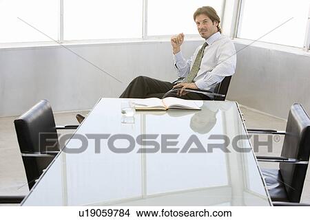Picture - Business man sitting at conference table, portrait. Fotosearch