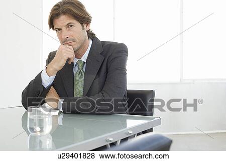 Business man sitting at conference table, portrait View Large Photo Image Stock Photo - Business man sitting at conference table, portrait. Fotosearch